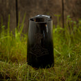 Load image into Gallery viewer, Et Vikingekrus Thors Hammer Horn (600-800 ml) med et indgraveret design, der ligner Thors Hammer, hviler på en plet græs, med en forvitret trævæg i baggrunden.