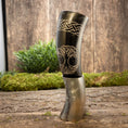 Load image into Gallery viewer, Drikkehorn Yggdrasil med Mønster, en poleret hornkar, der minder om traditionelle drikkehorn, hviler på en træoverflade med mos og grønt i baggrunden. Denne udsøgt udformede tankard byder på indviklede graveringer og et detaljeret design af et træ med indvævede grene og rødder - perfekt til naturentusiaster eller vikingemarkeder aficionados.