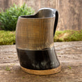 Load image into Gallery viewer, Et udsøgt håndlavet Vikingekrus Bark Horn (600-800 ml) med en trælignende tekstur på den øverste del og en glat, blank sort underdel, elegant vist på en rustik træoverflade med frodig grønt i baggrunden.