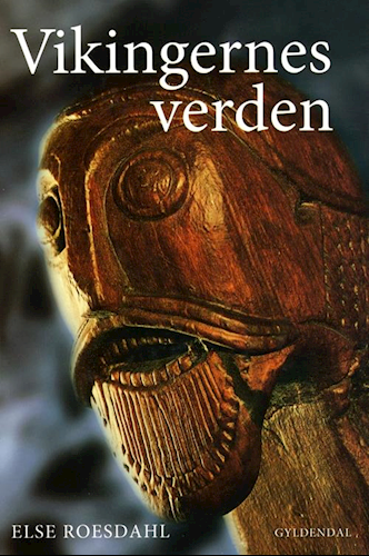 Forsiden af "Vikingernes Verden" viser et detaljeret nærbillede af et vikingeskibs galionsfigur i træ, prydet med indviklede udskæringer, alt sammen sat på en mørk baggrund, der fremkalder vikingetidens ånd. Titlen er markant placeret øverst, mens Else Roesdahls navn og forlag Gyldendal er placeret nederst.