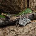 Load image into Gallery viewer, En detaljeret, bådformet metallisk broche i 925s Sterling sølv hviler på et groft stykke bark. Det indviklede design fanger lyset og viser dets håndværk. Grønt løv i den slørede baggrund tilføjer et naturligt touch til scenen.
