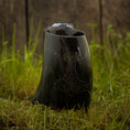 Load image into Gallery viewer, Vikingekrus Thors Hammer Horn (600-800 ml), et indviklet udskåret drikkehorn udsmykket med traditionelle nordiske designs, sidder oprejst på en plet af grønt græs. En forvitret træbaggrund tilføjer en rustik følelse til scenen, med Thors Hammer subtilt ætset i bunden.
